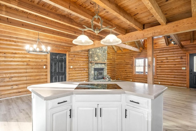 kitchen with hanging light fixtures, white cabinetry, rustic walls, and beamed ceiling