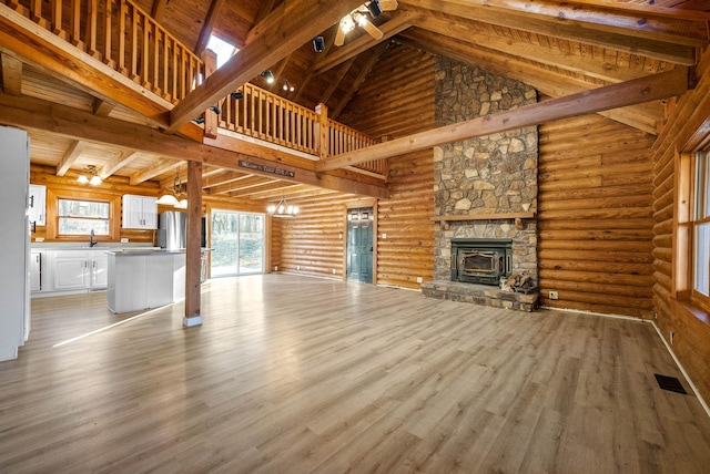 unfurnished living room with sink, wood ceiling, light hardwood / wood-style flooring, rustic walls, and high vaulted ceiling