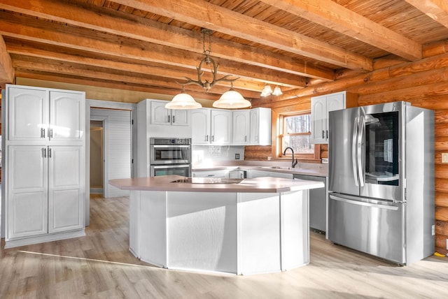 kitchen with beam ceiling, white cabinetry, appliances with stainless steel finishes, a kitchen island, and log walls