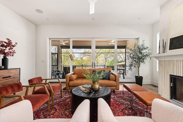 living room with a fireplace, baseboards, and wood finished floors