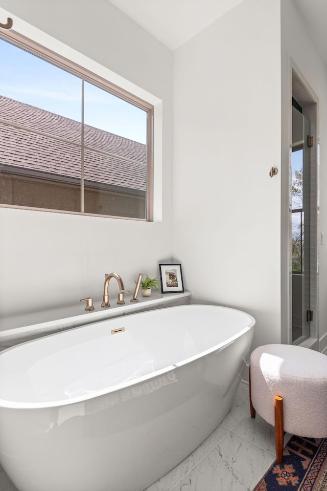 bathroom featuring a soaking tub and marble finish floor