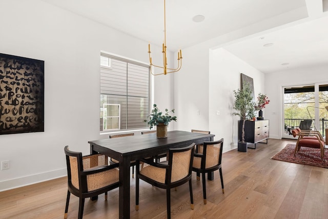 dining space featuring baseboards, light wood finished floors, and a chandelier