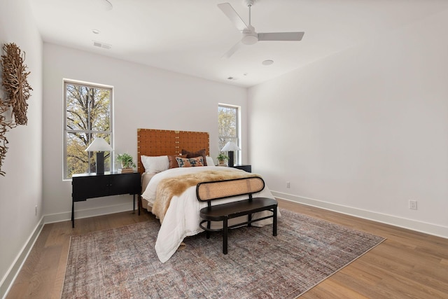 bedroom with visible vents, baseboards, wood finished floors, and a ceiling fan