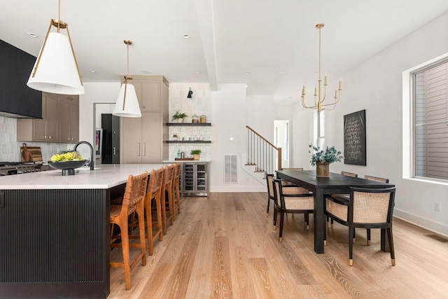 dining space with visible vents, wine cooler, light wood-style floors, and stairway