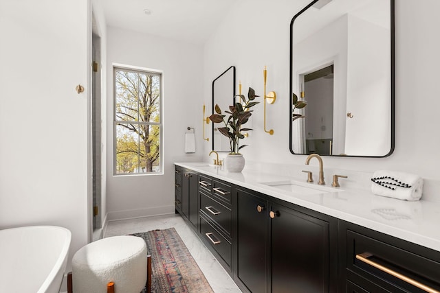 full bath featuring double vanity, plenty of natural light, marble finish floor, and a sink