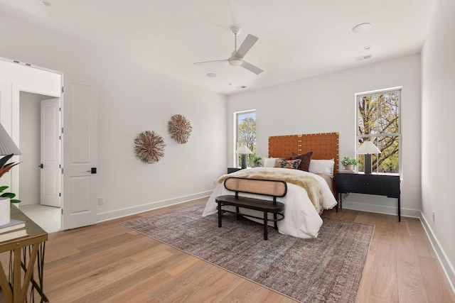 bedroom with visible vents, light wood-style flooring, baseboards, and ceiling fan