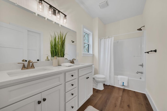 full bathroom featuring hardwood / wood-style flooring, shower / tub combo with curtain, vanity, and toilet