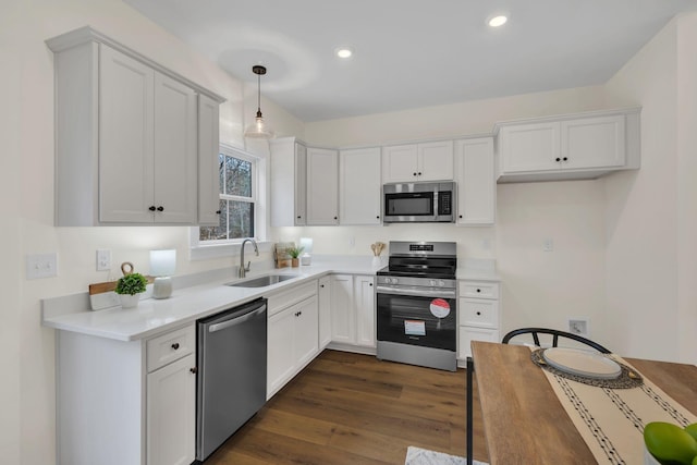 kitchen with appliances with stainless steel finishes, dark hardwood / wood-style floors, decorative light fixtures, sink, and white cabinets