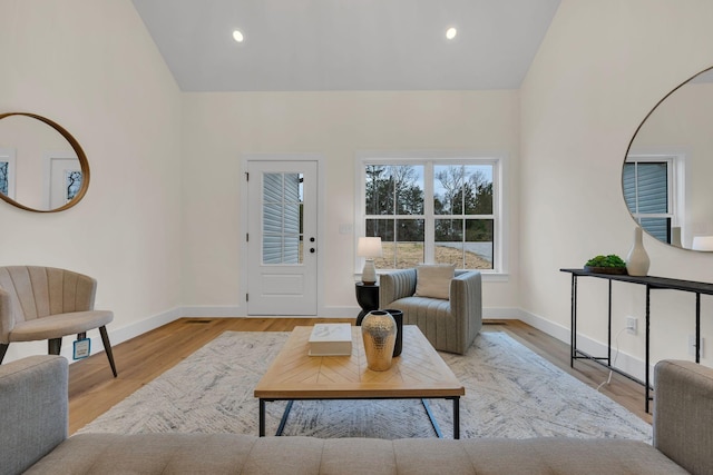 living room featuring lofted ceiling and light hardwood / wood-style floors