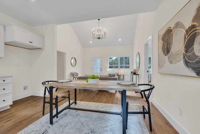 dining room featuring vaulted ceiling, a notable chandelier, and light hardwood / wood-style flooring