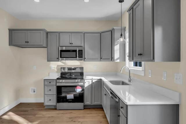 kitchen with sink, gray cabinets, hanging light fixtures, and stainless steel appliances