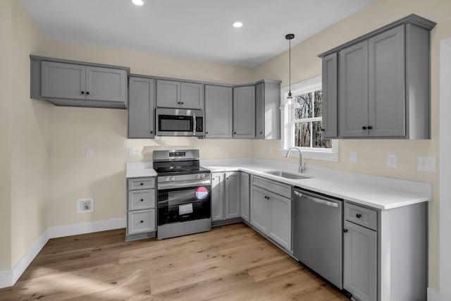 kitchen with sink, gray cabinets, pendant lighting, and stainless steel appliances