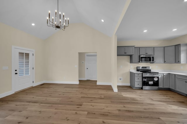 kitchen with appliances with stainless steel finishes, decorative light fixtures, light wood-type flooring, gray cabinetry, and high vaulted ceiling