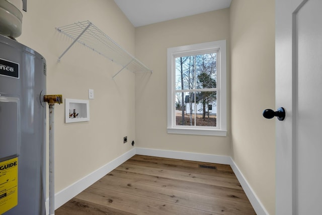 clothes washing area featuring hookup for an electric dryer, light hardwood / wood-style floors, washer hookup, and electric water heater