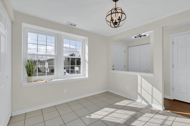 unfurnished dining area featuring light tile patterned floors and a chandelier