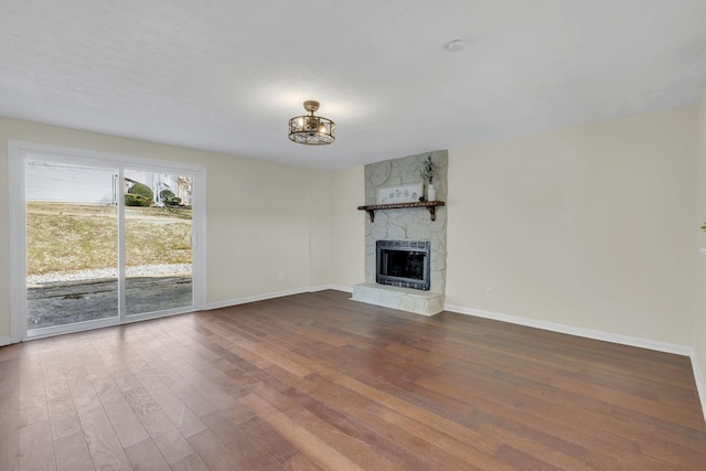 unfurnished living room with hardwood / wood-style flooring, heating unit, a chandelier, and a fireplace