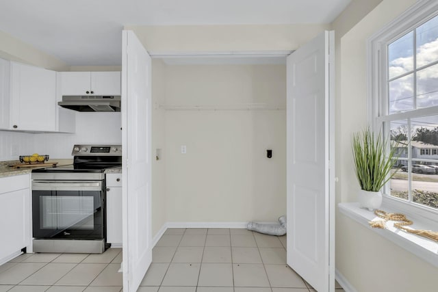 kitchen with light tile patterned flooring, white cabinets, a healthy amount of sunlight, and electric stove