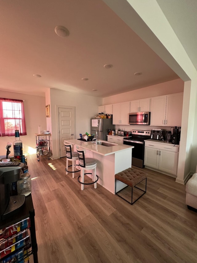 kitchen featuring appliances with stainless steel finishes, a breakfast bar area, white cabinets, and light wood-type flooring