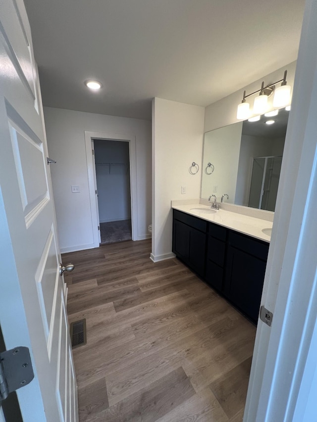 302 Williams Ave Unit 110, Madison, TN 37115 - bathroom featuring a shower stall, a sink, double vanity, visible vents, and wood finished floors