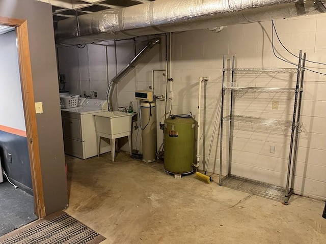 basement featuring washing machine and dryer, sink, and water heater