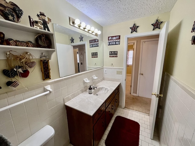 bathroom featuring a textured ceiling, vanity, tile patterned floors, and tile walls