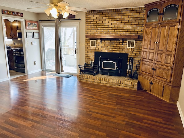 unfurnished living room featuring a fireplace, a textured ceiling, dark hardwood / wood-style floors, and ceiling fan