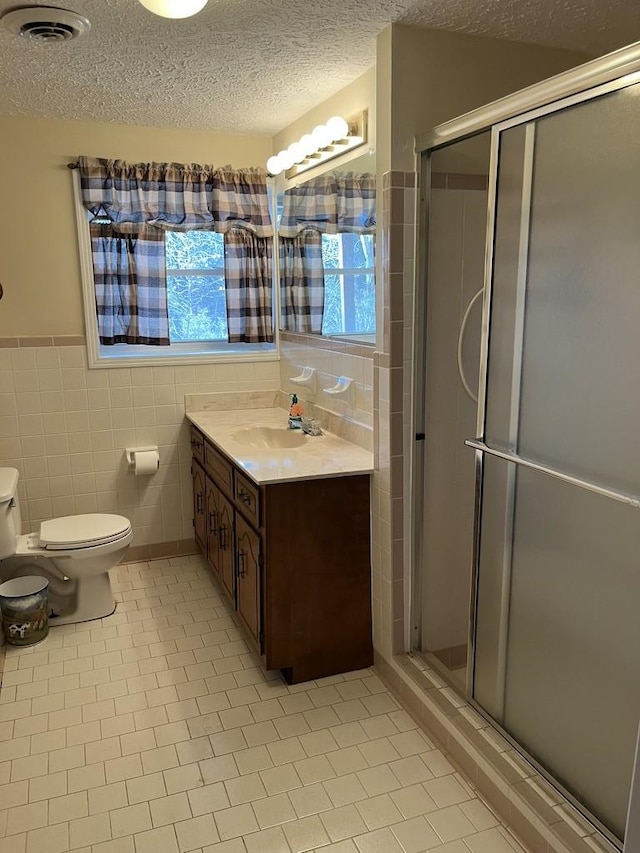 bathroom featuring a shower with shower door, tile patterned floors, and tile walls