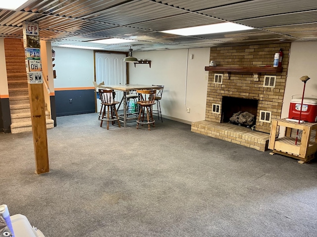 basement with carpet floors, bar area, and a brick fireplace