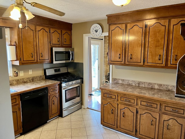 kitchen with stainless steel appliances, ceiling fan, light tile patterned floors, and a textured ceiling