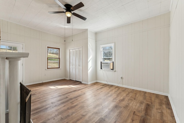 unfurnished living room with hardwood / wood-style floors, ceiling fan, and wood walls