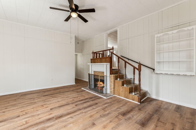 unfurnished living room with crown molding, ceiling fan, hardwood / wood-style floors, and a brick fireplace