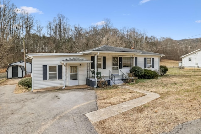 view of front facade featuring a shed, cooling unit, a front lawn, and covered porch