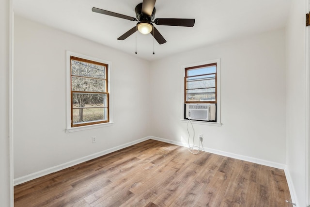 empty room with cooling unit, ceiling fan, a healthy amount of sunlight, and light hardwood / wood-style flooring