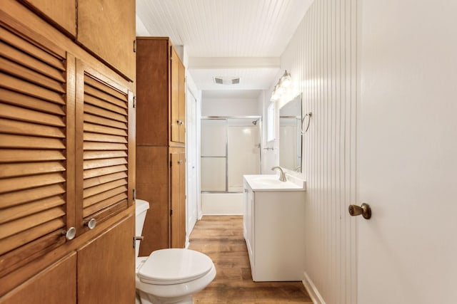 full bathroom featuring combined bath / shower with glass door, beam ceiling, vanity, wood-type flooring, and toilet