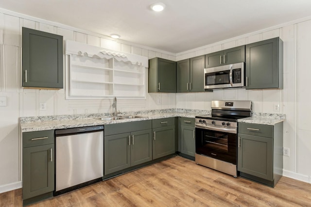 kitchen featuring appliances with stainless steel finishes, sink, light hardwood / wood-style floors, crown molding, and light stone countertops