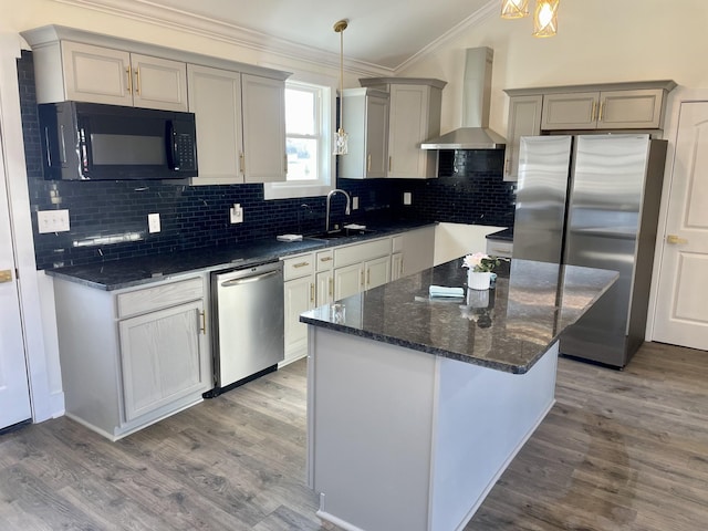 kitchen featuring wall chimney exhaust hood, sink, hanging light fixtures, and appliances with stainless steel finishes