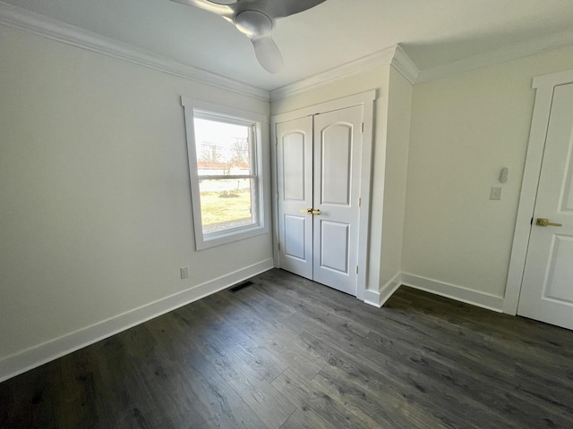 unfurnished bedroom with crown molding, dark wood-type flooring, a closet, and ceiling fan