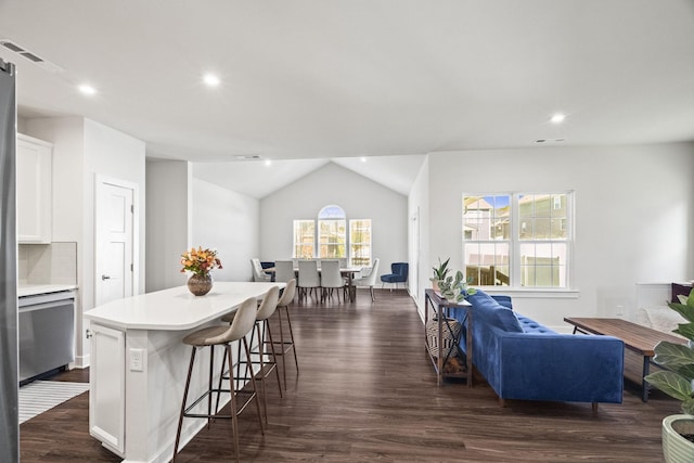 kitchen with a kitchen bar, white cabinetry, a center island, and dark hardwood / wood-style flooring