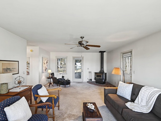 carpeted living room with ceiling fan and a wood stove