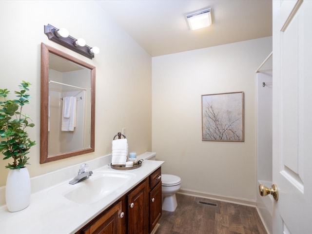 bathroom with hardwood / wood-style flooring, toilet, a shower, and vanity