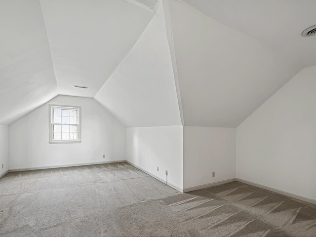 additional living space featuring vaulted ceiling and light colored carpet