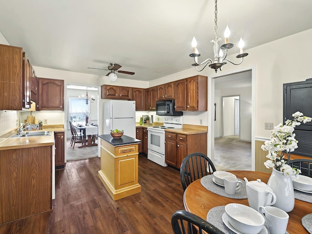 kitchen with sink, dark wood-type flooring, white appliances, ceiling fan with notable chandelier, and a center island