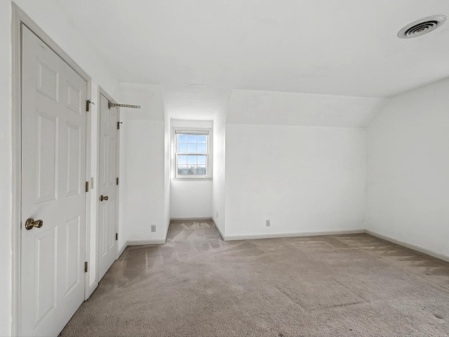 additional living space with vaulted ceiling and light carpet