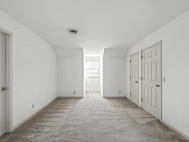 bonus room with light colored carpet and lofted ceiling