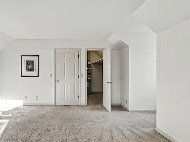 interior space featuring light colored carpet, a closet, a spacious closet, and lofted ceiling