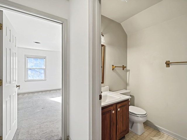 bathroom featuring vanity, toilet, and vaulted ceiling