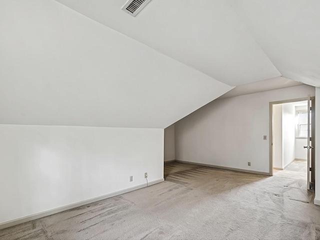 additional living space featuring light colored carpet and lofted ceiling