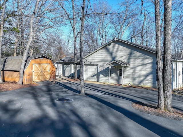 view of side of home featuring a garage and a storage shed