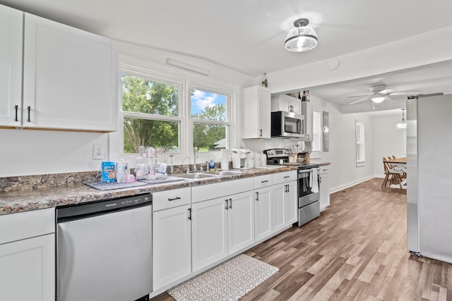 kitchen with sink, white cabinets, light hardwood / wood-style flooring, and appliances with stainless steel finishes