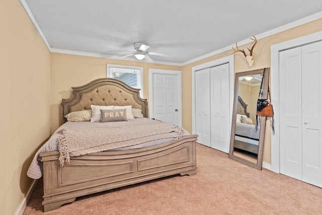 bedroom featuring light colored carpet, two closets, ceiling fan, and ornamental molding